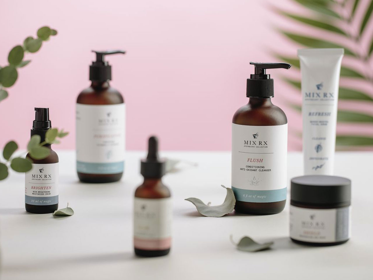 Photograph of six Mix RX skincare products laid on white surface with leaves and plantlife against a pink background